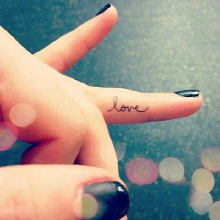 love finger tattoo, woman with a black nail polish, small tattoos for guys, hand in front of a black background