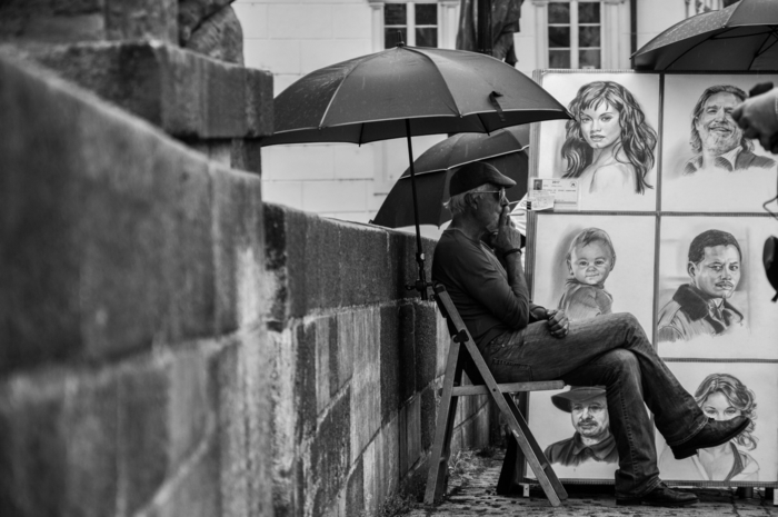 man sitting on a chair, smoking a cigarette, surrounded by drawings of celebrities, girl drawing