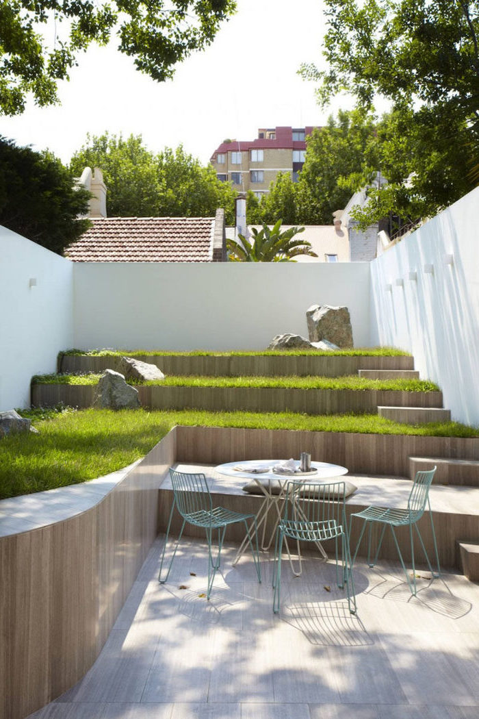 multi-leveled planted green grass, with large rocks, small garden ideas, metal garden furniture, on a wooden floor