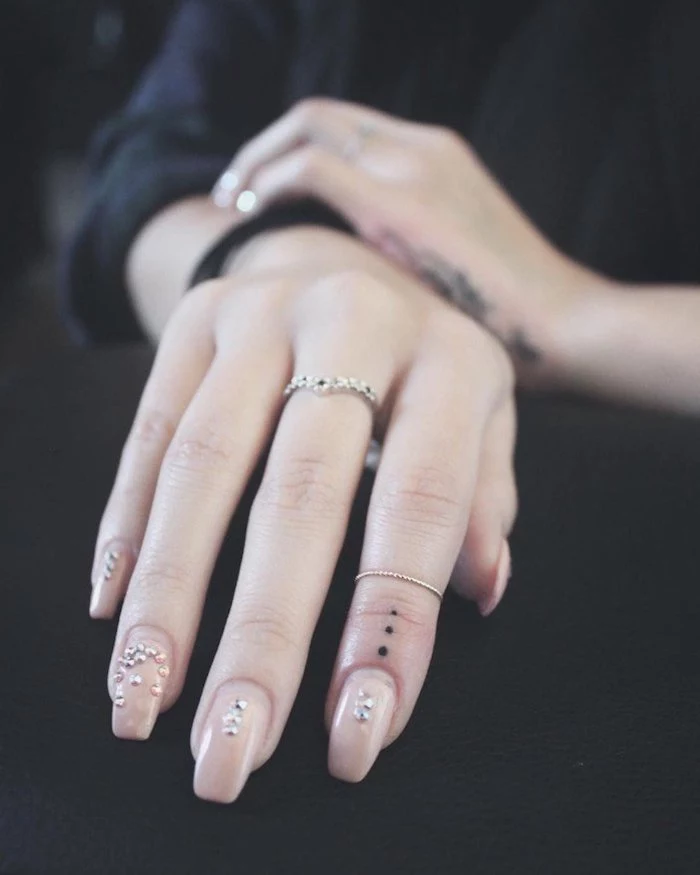 small dots, tattoo on the finger, cute finger tattoos, nude nail polish with rhinestones, black shirt