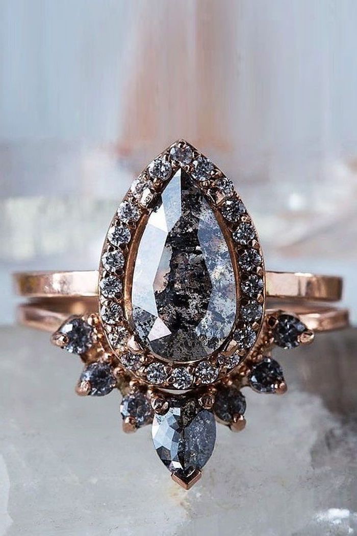 teardrop shaped onyx stone, rose gold band, beautiful wedding rings, blurred background