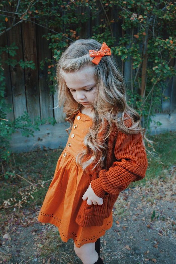orange bow, long blonde wavy hair, hairstyles for girls with long hair, orange cardigan and dress