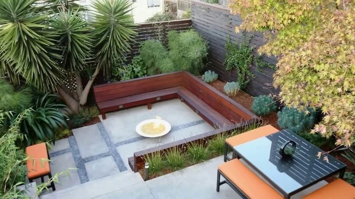 large wooden bench, fire pit in the middle, small backyard designs, planted palm trees and bushes