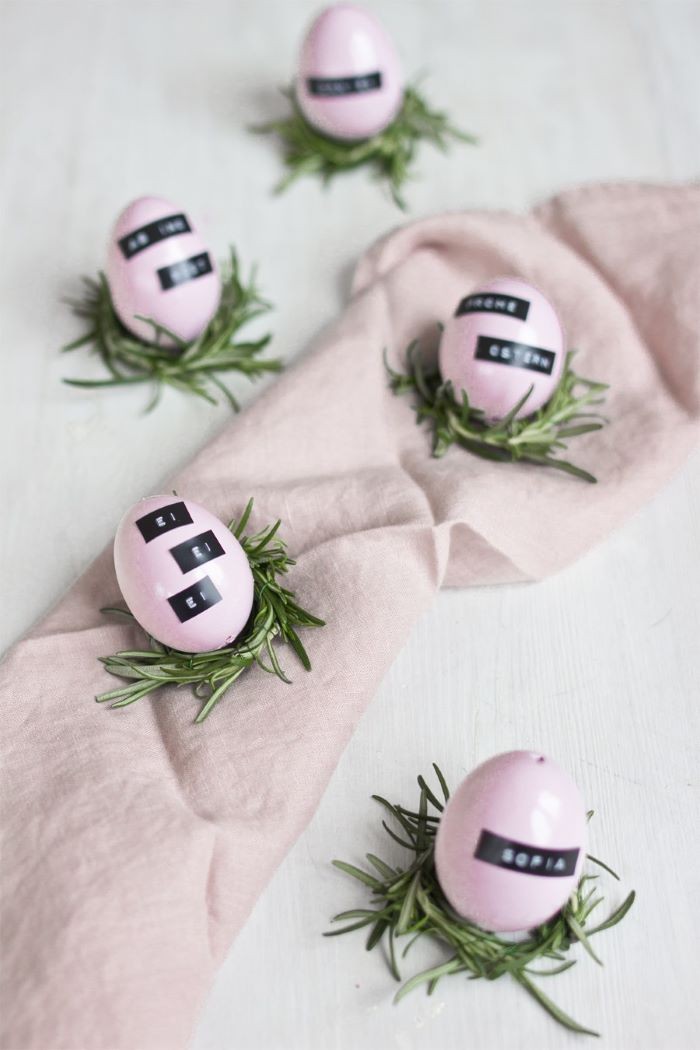 pink eggs, scattered on a pink table runner, with rosemary branches, and name tags, easter centerpieces