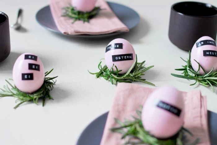 grey plate settings, with pink napkins, pink eggs, on rosemary branches, scattered across the table, diy easter decorations