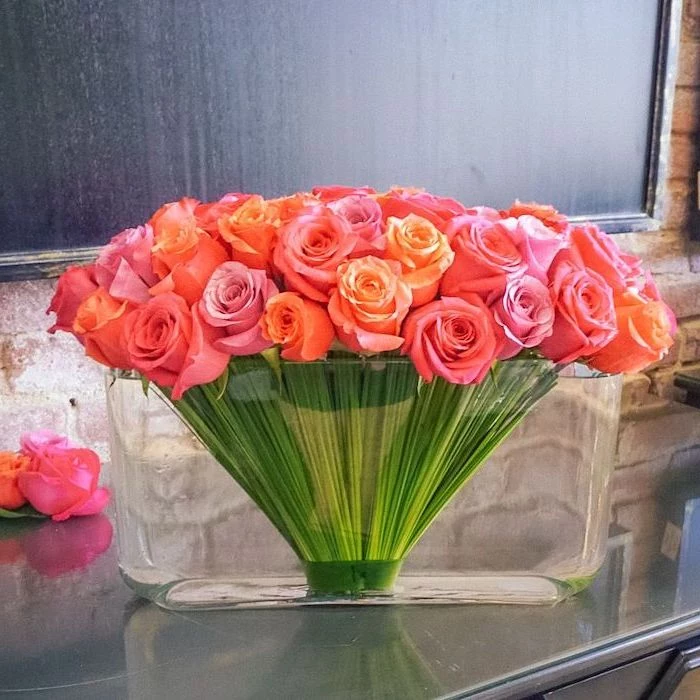 pink and orange roses, in a large glass vase, how to arrange flowers, on a grey countertop