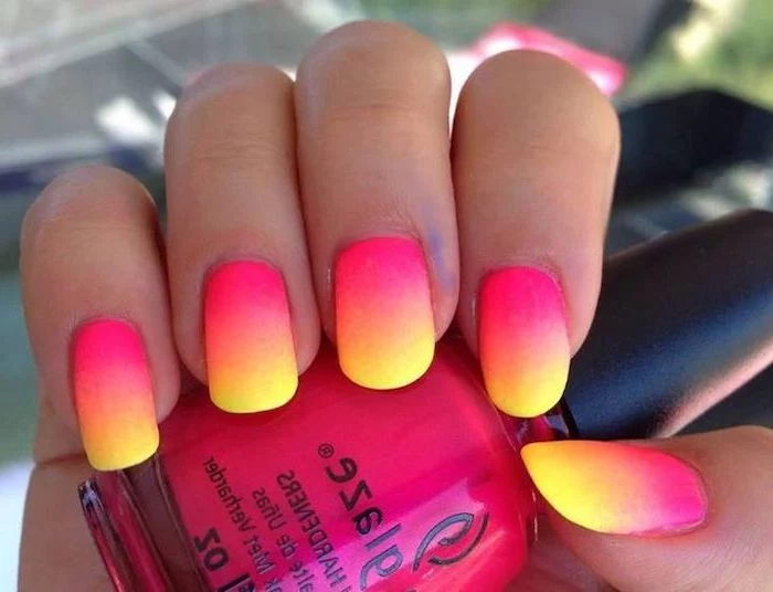 pink orange and yellow ombre, neon nail polish, long squoval nails, pink and gold nails, hand holding a pink nail polish bottle