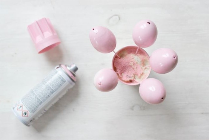 pink spray paint, five pink eggs, on wooden skewers, diy easter decorations, on a white countertop