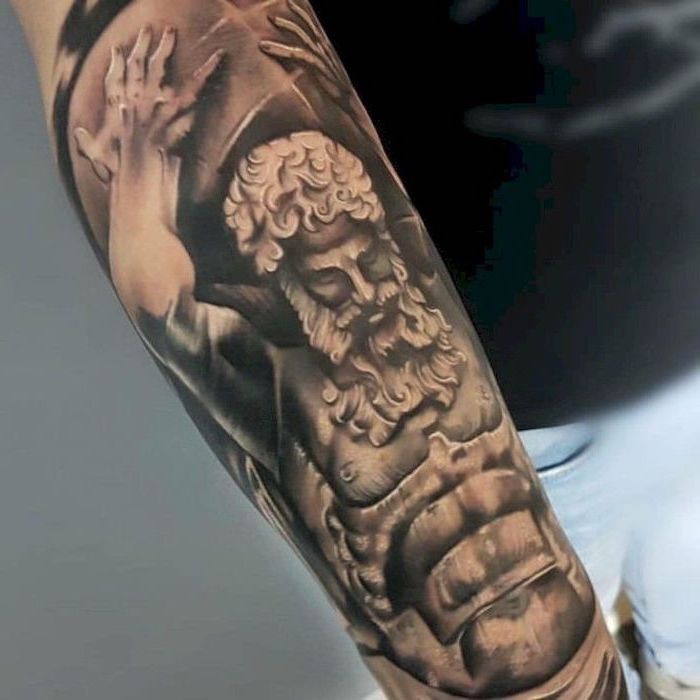 religious theme, forearm tattoo, man holding a weight, cool tattoos for guys, man wearing black shirt and jeans