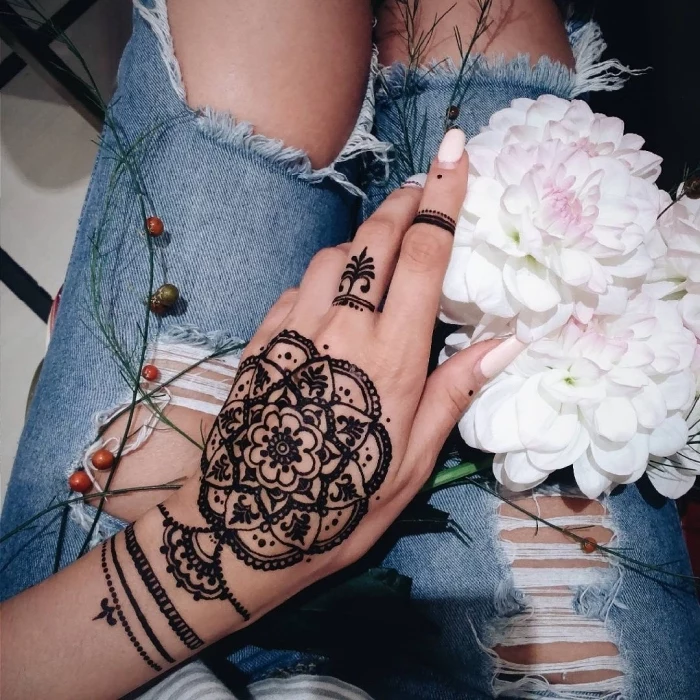 large henna tattoo, pink nail polish, lion finger tattoo, hand holding a flower bouquet