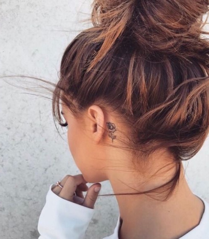 brown hair in a messy bun, small tattoo, small rose behind the ear tattoo, white blouse