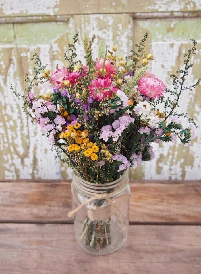 small colourful flower bouquet, in a mason jar, beautiful flower arrangements, on a wooden table, in a rustic style