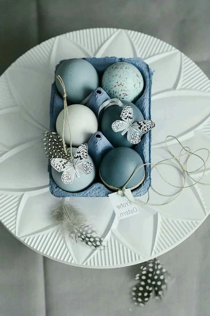 blue egg carton, on a white plate, tie dye easter eggs, full of shades of blue eggs, butterflies and feathers