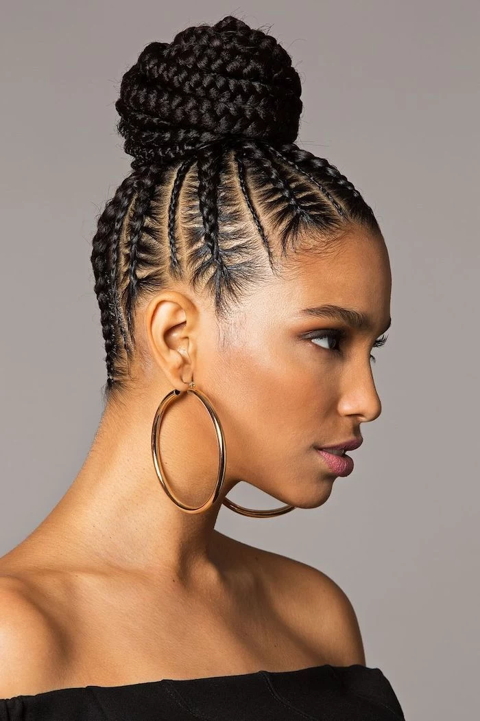braided black hair, in a bun, large hoops earrings, easy to do hairstyles, grey background