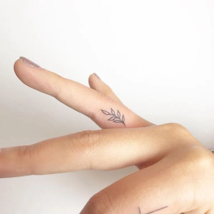 rose finger tattoo, small branch, ring finger tattoo, hand in front of a white background
