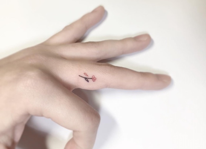 small flower, middle finger tattoo, hand in front of a white background, crown finger tattoo