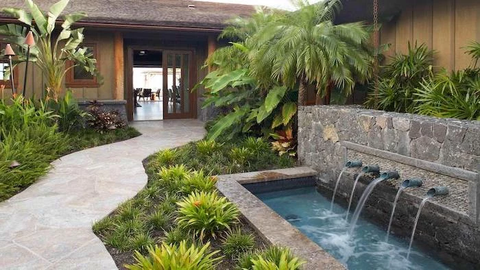 small fountains, cement tiled pathway, planted bushes and palm trees alongside it, backyard ideas for small backyards