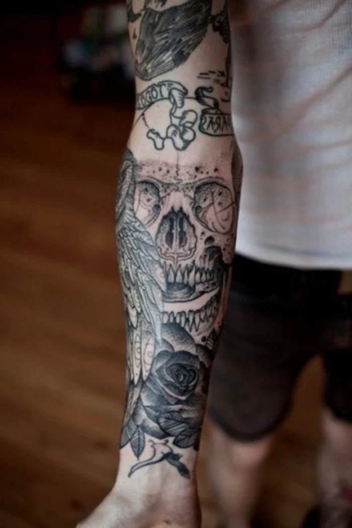 arm sleeve tattoo, with skull owl and roses, upper arm tattoos, man wearing a white shirt and jeans