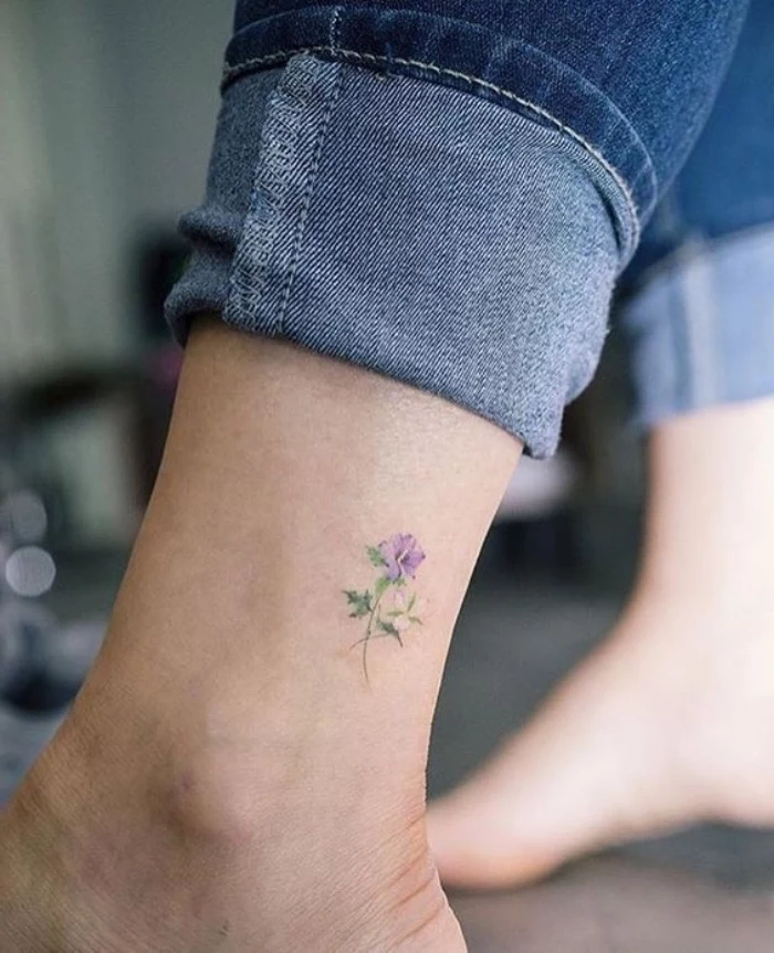 small flower ankle tattoo, cool small tattoos for guys, person wearing jeans, with bare feet