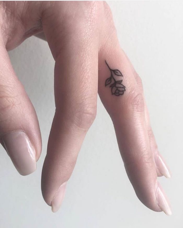 small rose, middle finger tattoo, nude nail polish, crown finger tattoo, hand in front of a white background