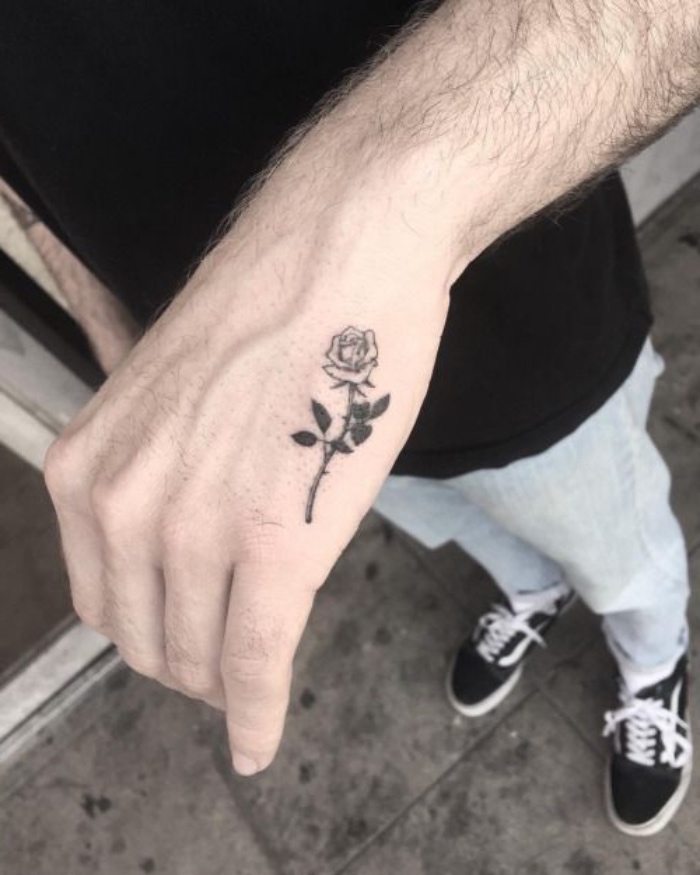 small rose hand tattoo, small forearm tattoo, man wearing washed jeans, black vans shoes, black shirt