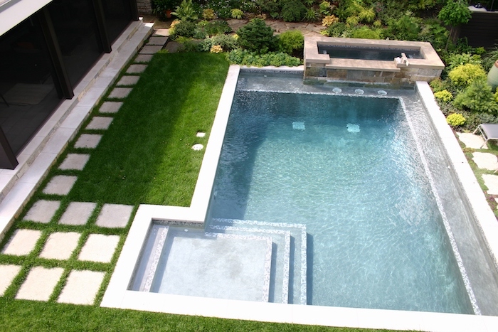 small swimming pool, with a small hot tub, small yard landscaping, ceramic tiles over a grass patch