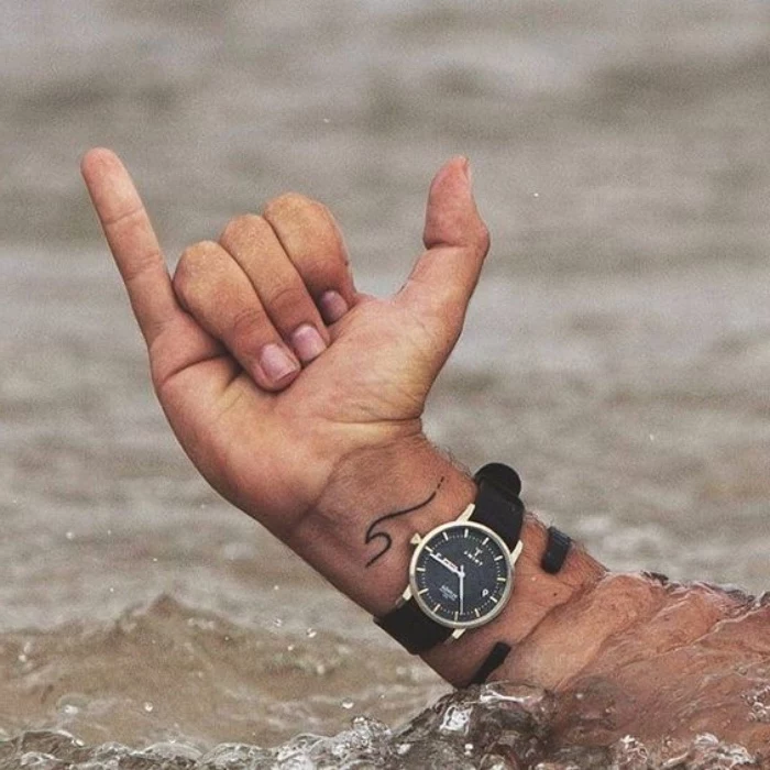 small wave wrist tattoo, small forearm tattoo, hand coming out of water, wearing a black watch
