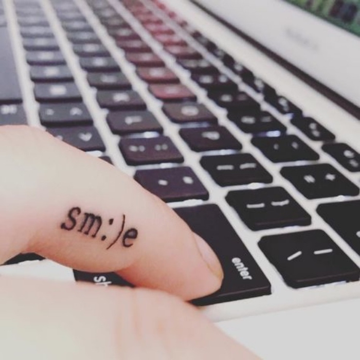 smile finger tattoo, person typing on a macbook keyboard, small lotus flower tattoo