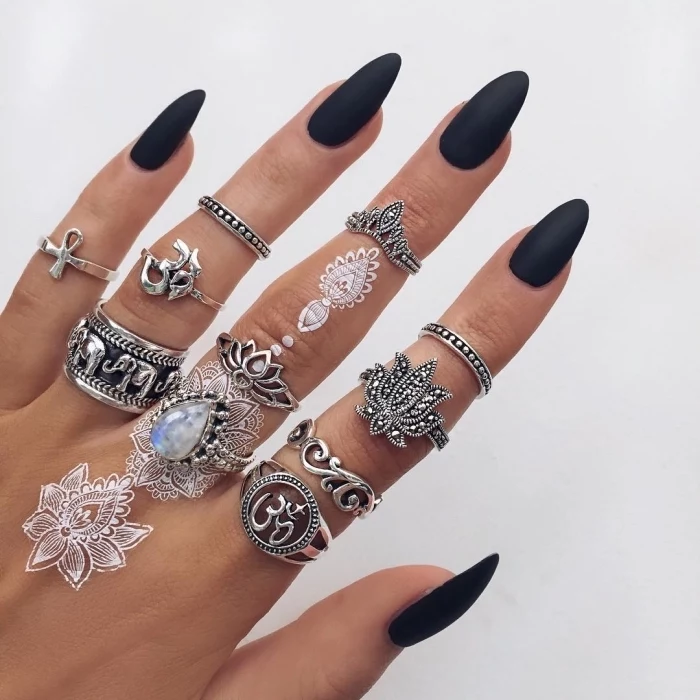 black matte nail polish, white henna tattoos, lots of silver stackable rings, crown finger tattoo