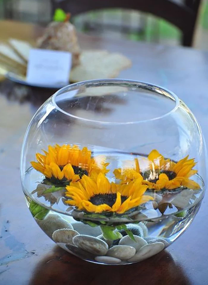 small round glass vase, sunflowers and river stones, floating in it, flower arrangement pictures, on a wooden table