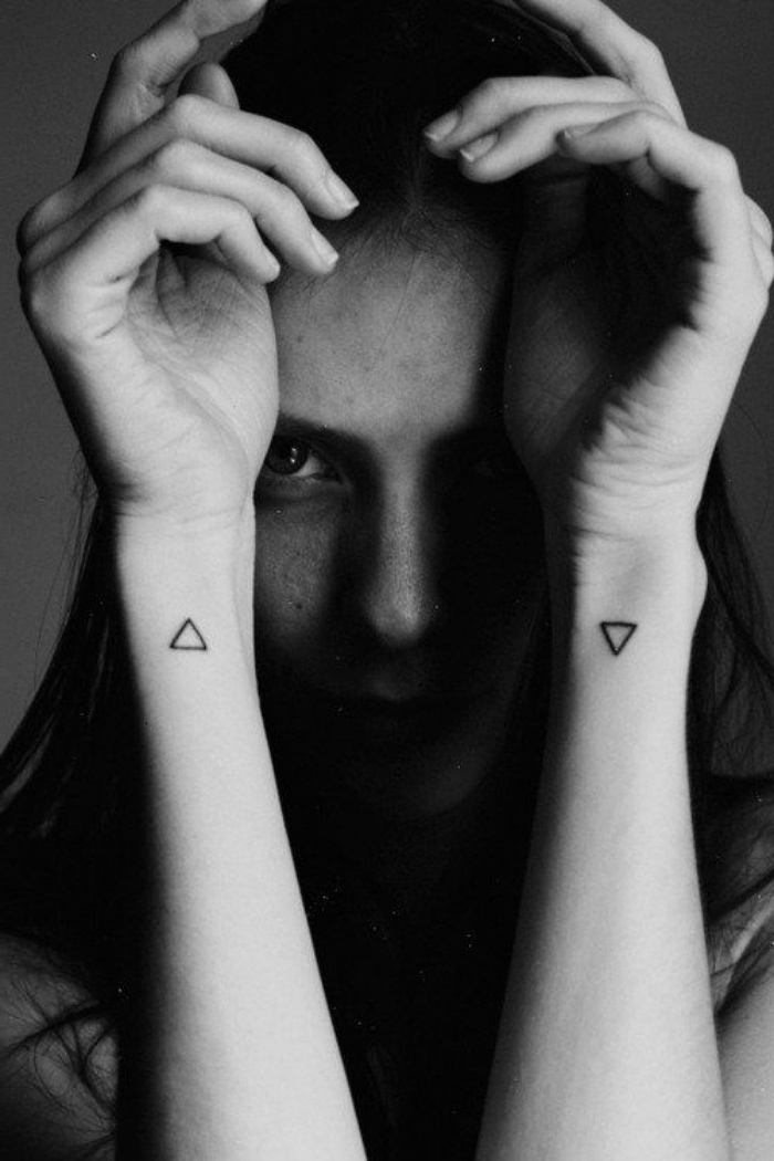 small triangles wrist tattoo, on both hands, woman with both hands, in front of her face, small matching tattoos