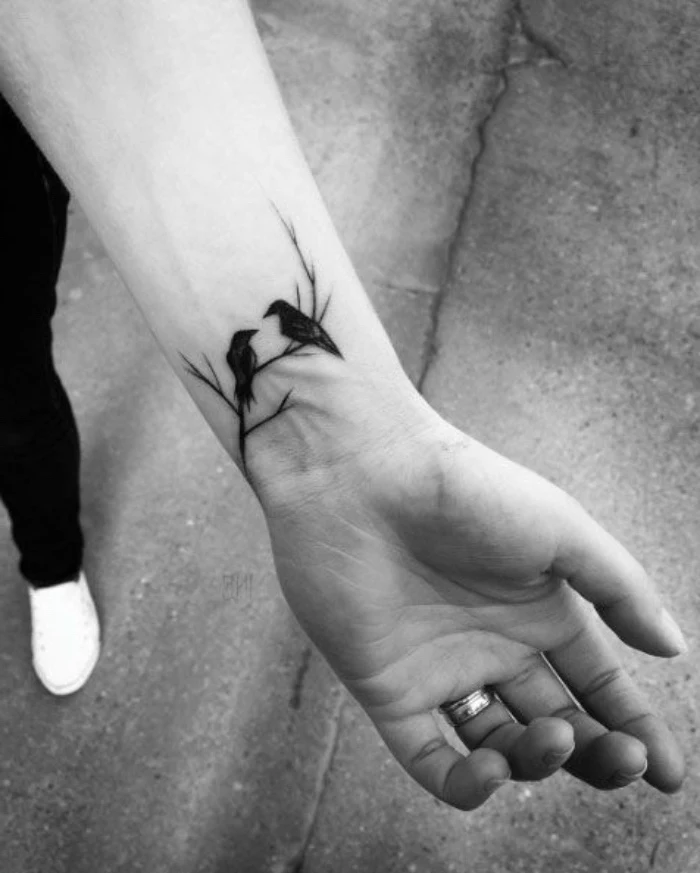 two birds on a tree branch wrist tattoo, person wearing white sneakers, small matching tattoos