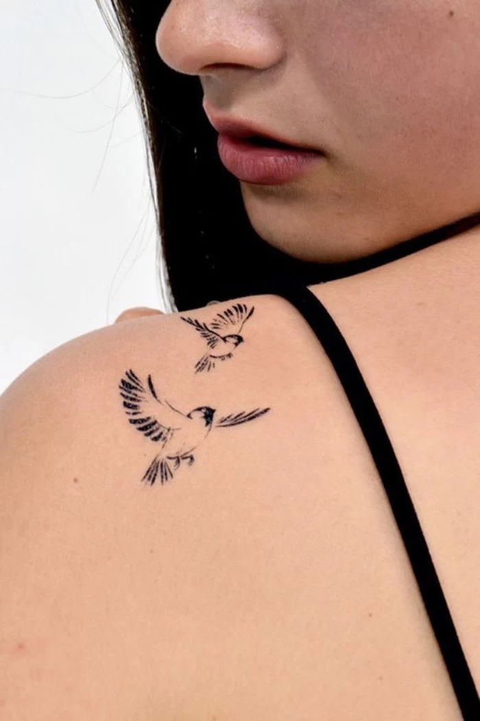 two birds flying away shoulder tattoo, woman with long black hair, small matching tattoos, black straps