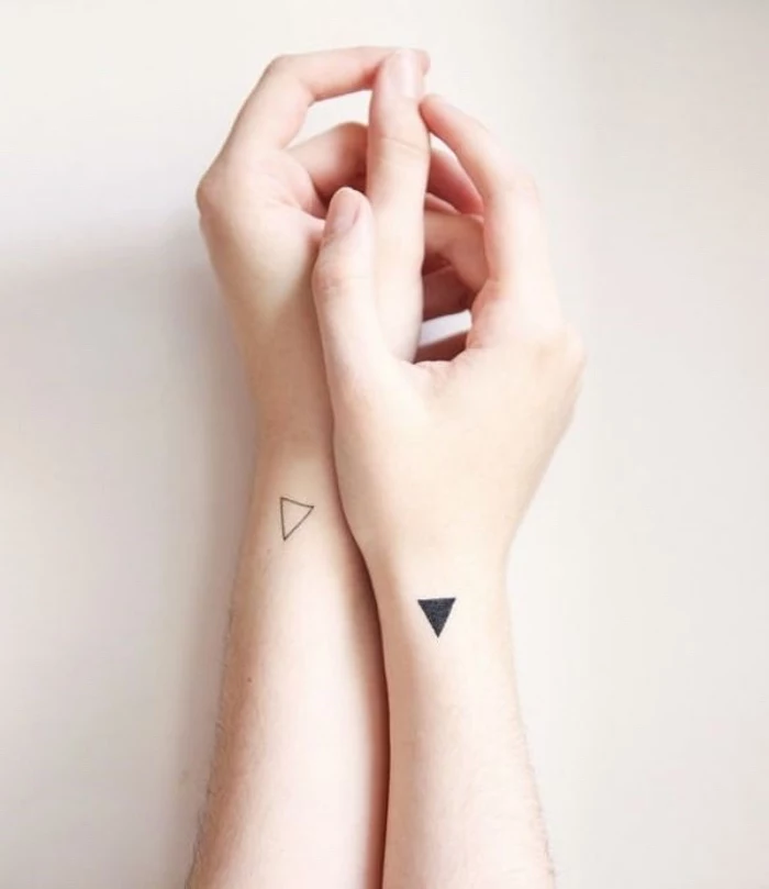 white and black triangle wrist tattoos, on both hands, best small tattoos for men, hands in front of a white background