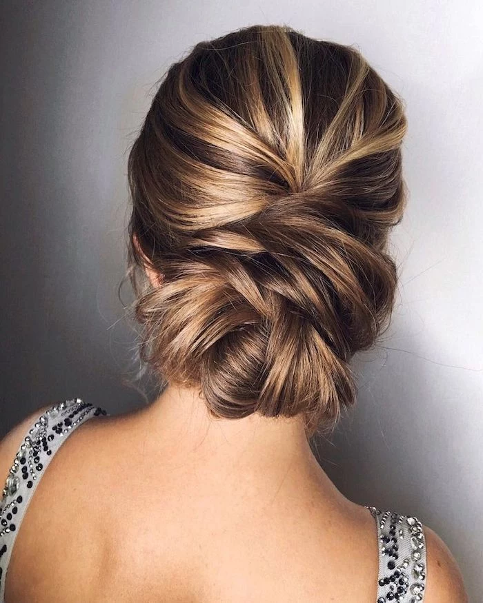 brown hair with highlights, loose updos, in a low updo, grey background, grey dress straps