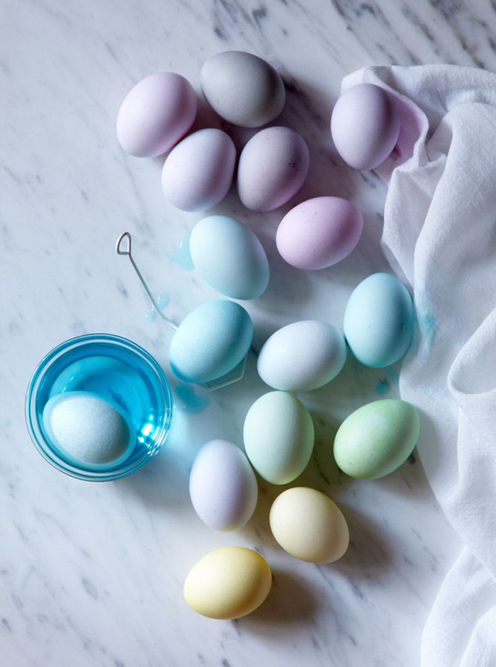 marble countertop, how to decorate easter eggs, ombre eggs, glass full of blue dye, purple and blue, green and yellow eggs