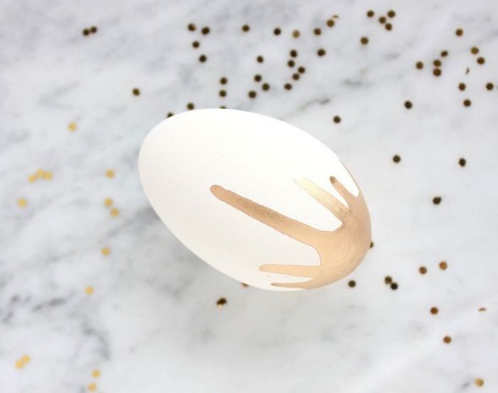 white egg, gold paint dripping, on a marble countertop, what is easter egg, golden confetti around