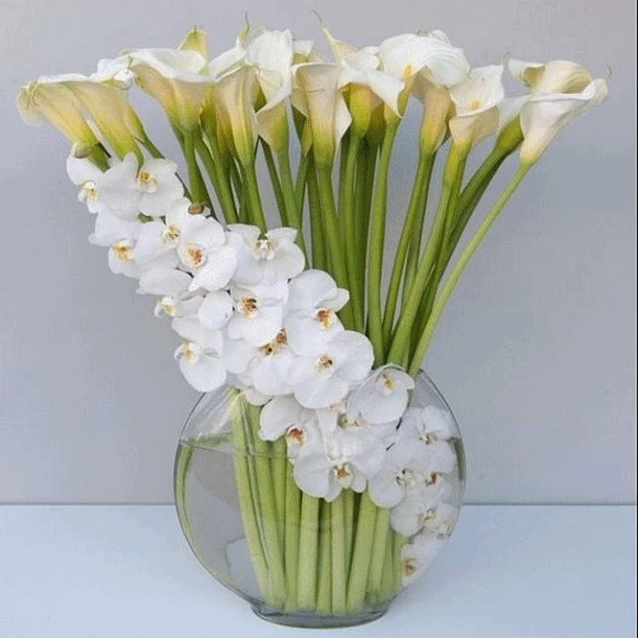 white lilies and magnolias, in a large round glass vase, on a white countertop, flower arrangements ideas