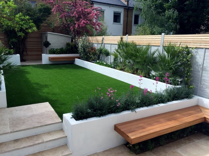 a grass parch, surrounded by planted trees bushes and flowers, small space gardening, wooden bench next to them