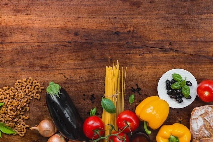 wooden countertop, healthy meal plans for women, aubergine and onions, peppers and tomatoes, olives and pasta