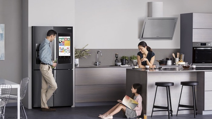 black and grey stainless steel kitchen appliances, two black bar stools, white and beige walls