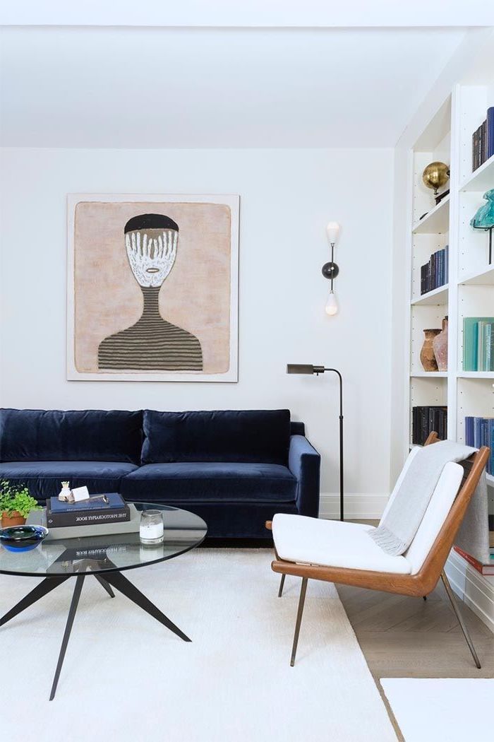 blue velvet sofa, white wooden armchair, minimalist living room, white carpet, glass coffee table