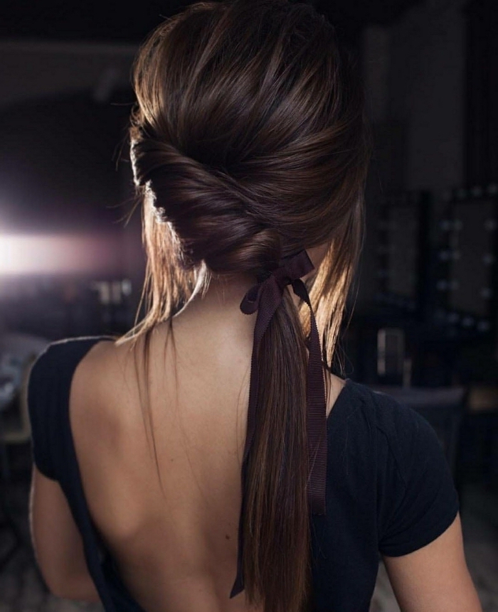 brown hair in a twisted, low ponytail, tied with a purple bow, hairstyles for teenagers, black top