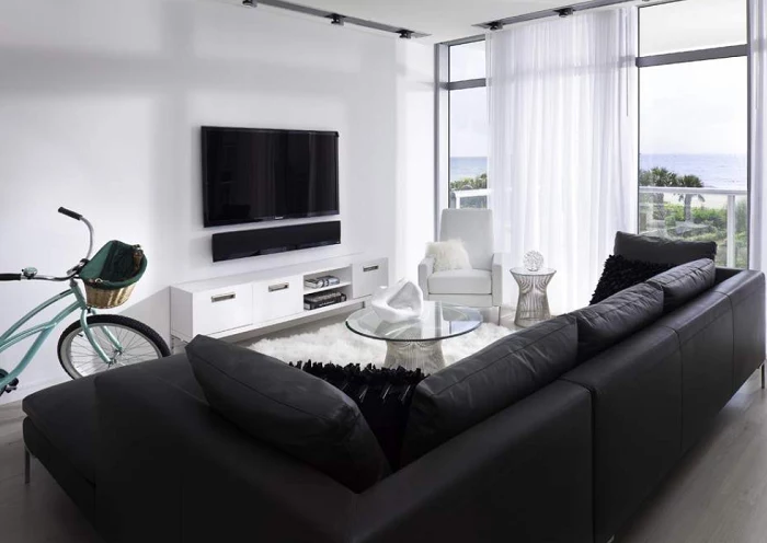 black leather sofa, white cabinet and armchair, glass coffee table, minimalist living room
