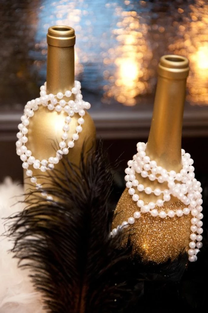 champagne bottles, painted in gold, decorated with pearls, black feathers, dining table centerpiece ideas
