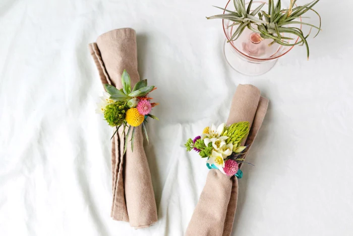 beige cotton napkin, table decoration ideas, floral napkin rings, small glass, tree branches inside