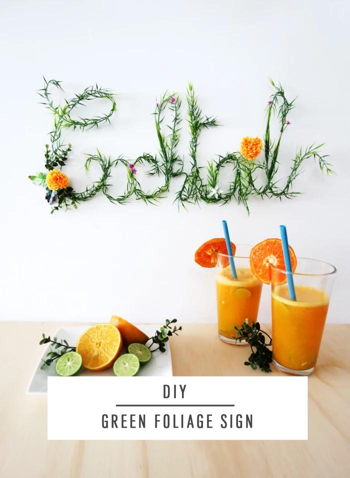 diy green foliage sign, living room wall decor ideas, two glasses, of orange juice, on a wooden table