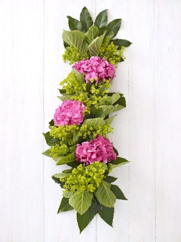 floral table runner, pink hydrangeas, green leaves, dining table centerpieces, wooden background