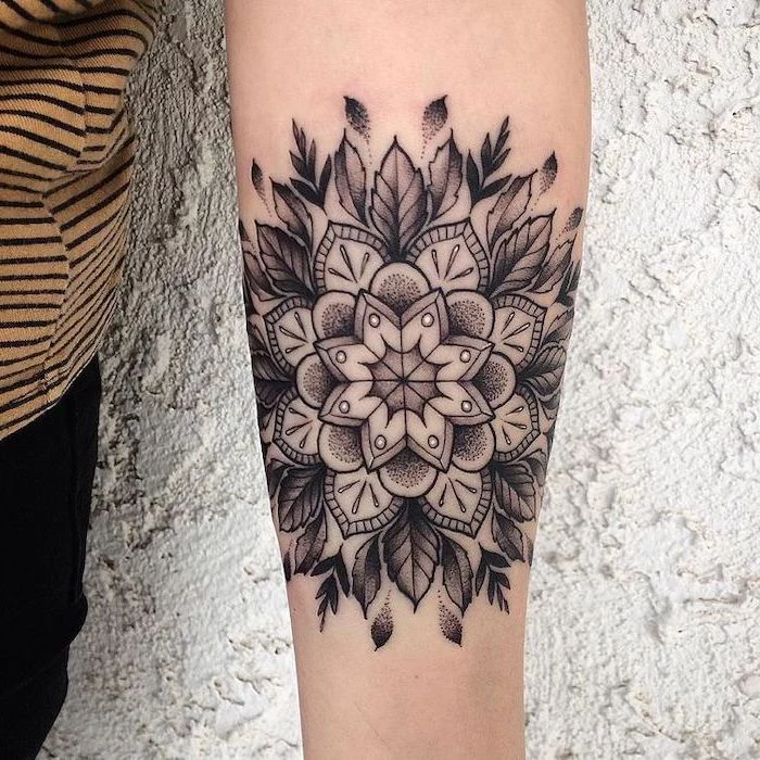 white background, forearm tattoo, lotus mandala tattoo, black pants, yellow and black, striped shirt