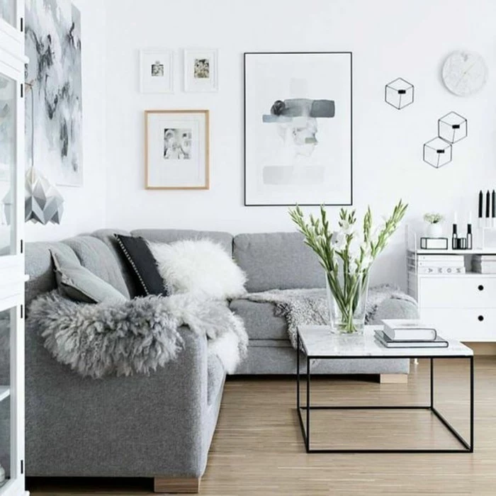 marble coffee table, grey corner sofa, light gray walls, framed hanging art, large glass vase